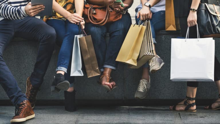 People sitting on wall with shopping bags