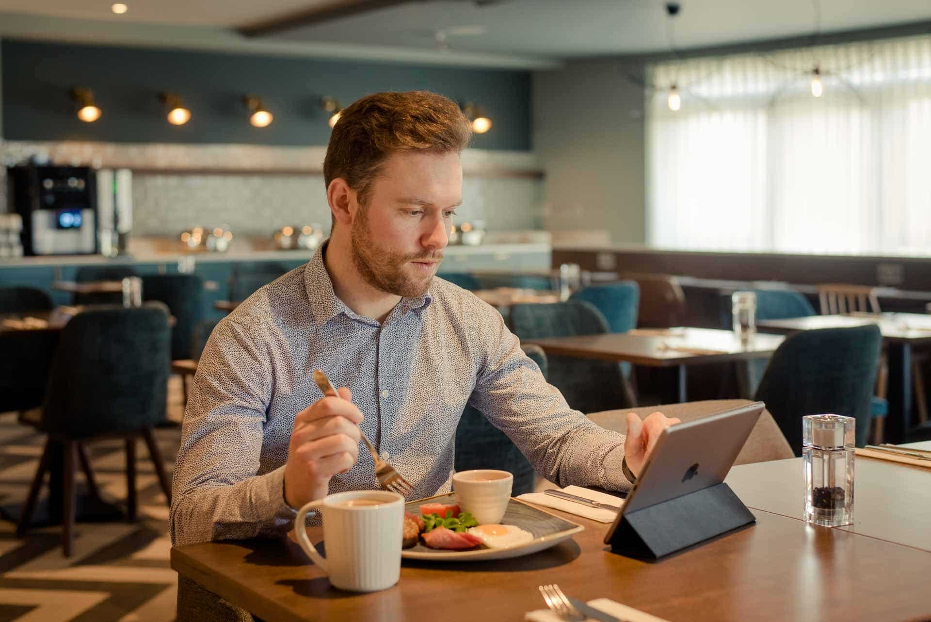 The Hoban Hotel Kilkenny business man eating Full Irish Breakfast while enjoying free wi-fi